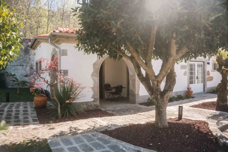 Garden path to a white house with stone arch